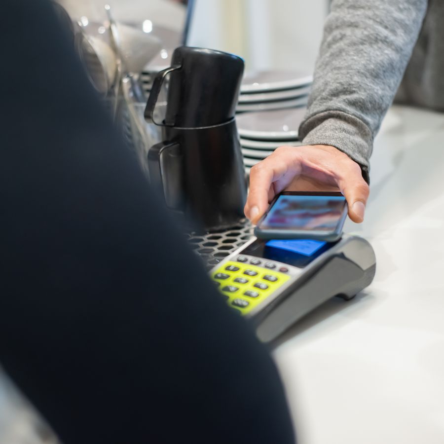 A customer tapping a phone to pay at a counter