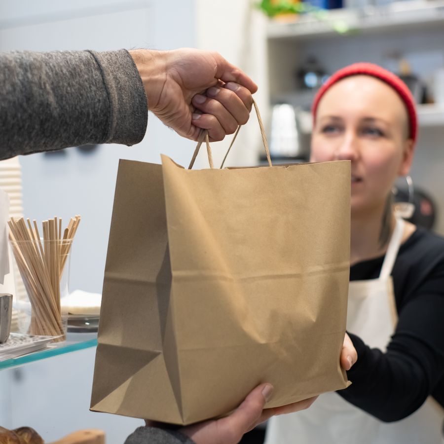 A cook handing a packed paper bag across the counter